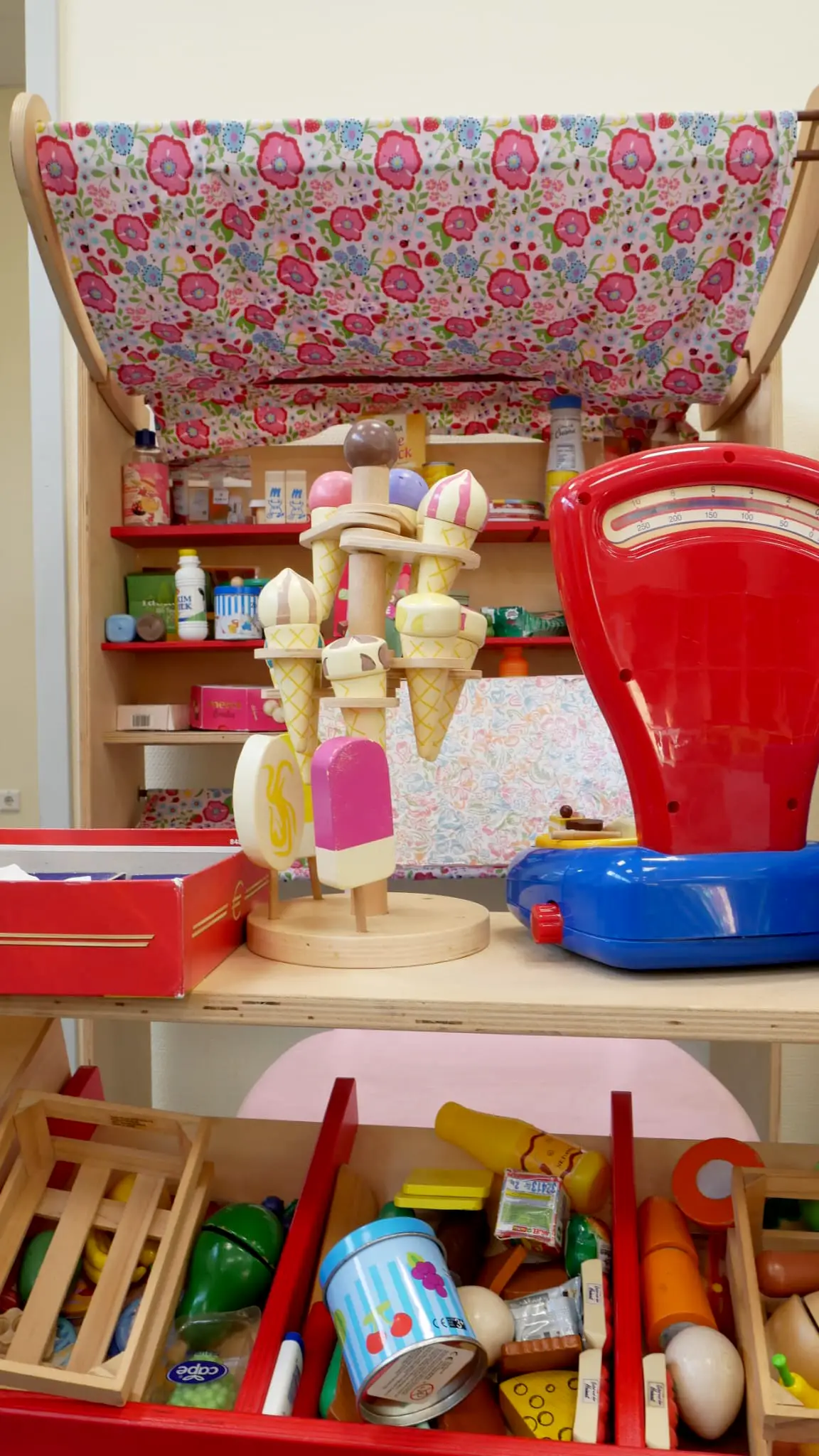 ottopankockschuledrevenack_ogs2 Bunte Spielzeugecke mit Holzspielzeug, Eiswaffeln und Verkaufsstand, liebevoll dekoriert mit einem geblümten Stoffdach.
